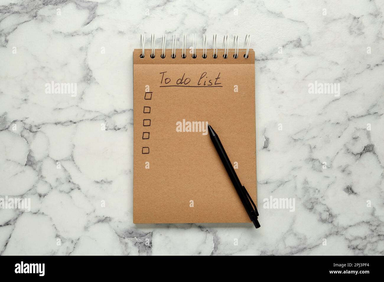 Notizblock mit ungefüllter Aufgabenliste und Stift auf weißem Marmortisch, Draufsicht Stockfoto