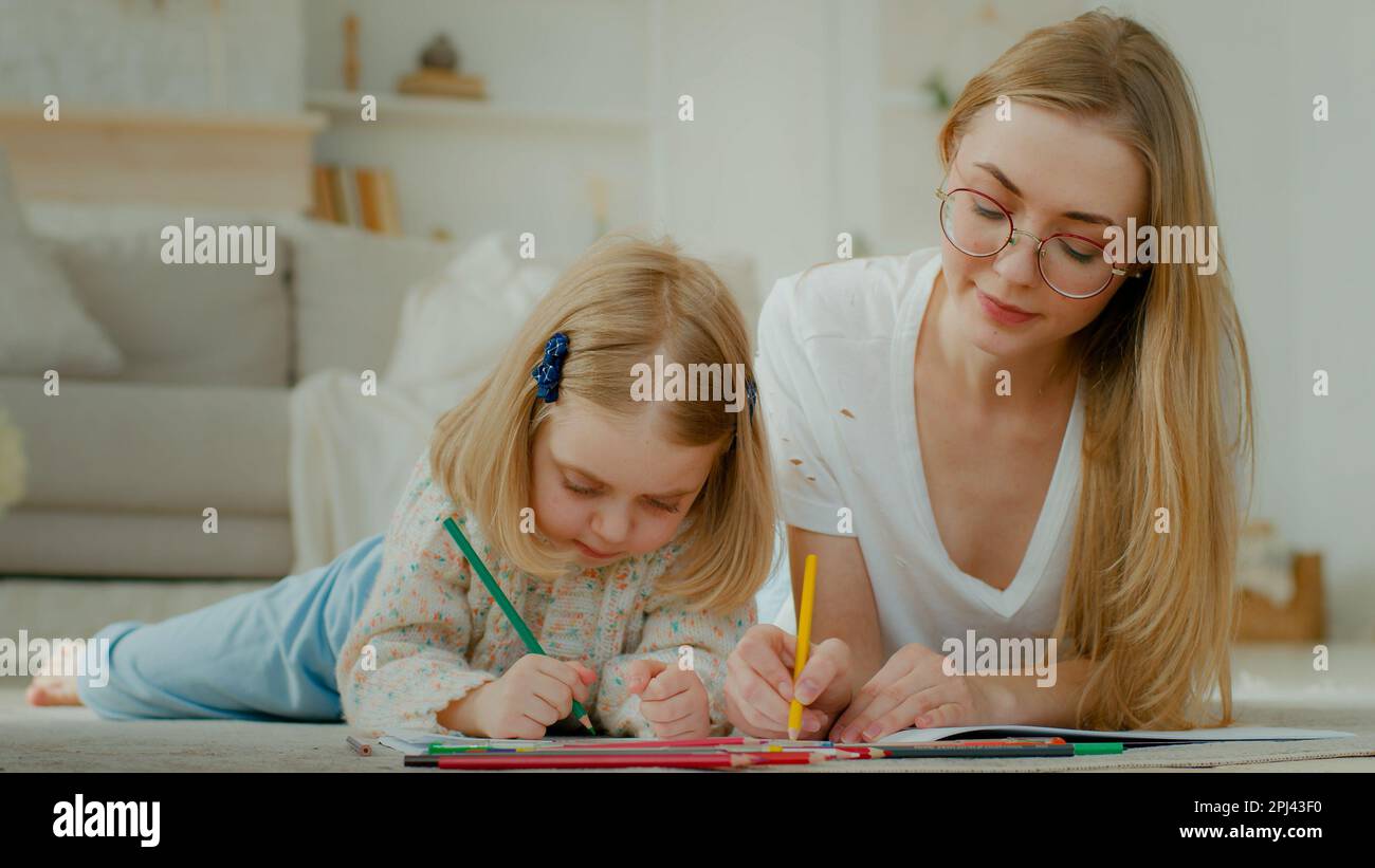 Kaukasische Mutter, die zu Hause auf dem Boden liegt, und kleine Adoptivkinder lieben es, zusammen zu ziehen. Tochter Baby Vorschulkind mit mutter Babysitter Stockfoto