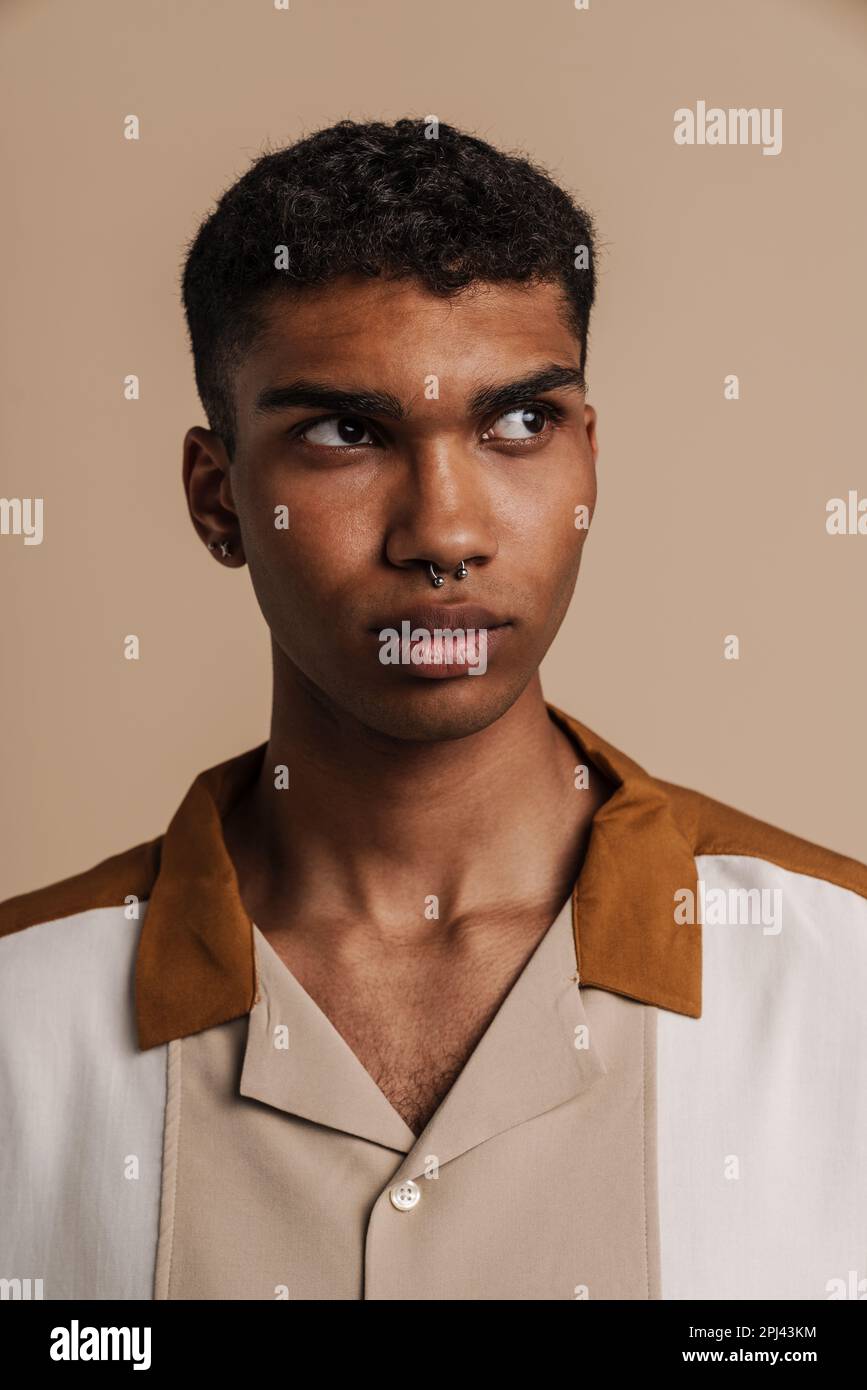 Porträt eines jungen, gutaussehenden, seriösen afrikaners mit beigefarbenem Hintergrund Stockfoto
