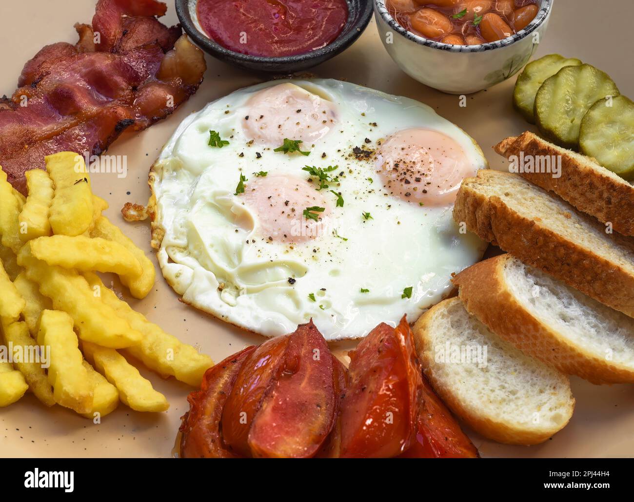 Gesundes englisches Frühstück mit Spiegeleiern, Speck, pommes frites, Bohnen und Tomaten Stockfoto