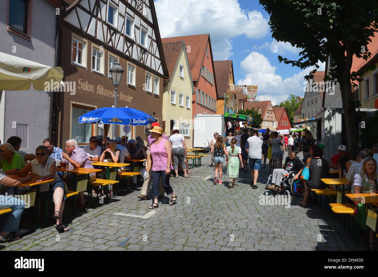 Deutschland, Bayern, Mittelfranken, Feuchtwangen: Tische und Bänke für den Konsum von Bier und Würstchen säumen die gepflasterten Straßen während des Volksf Stockfoto