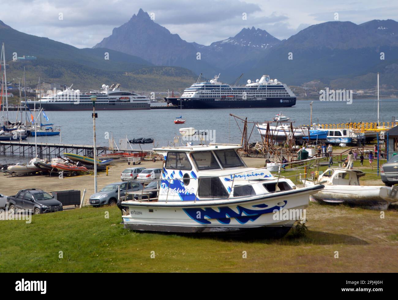 Argentinien, Tierra del Fuego, Ushuaia: Gestrandete Fischerboote mit Kreuzfahrtschiffanlegestellen im Hintergrund, mit Blick auf die Martial Mountains. Stockfoto