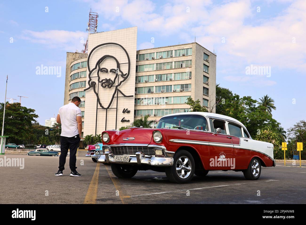 Oldtimer-Chevrolet auf dem Platz der Revolution gegen das Gebäude des Ministeriums für Information und Kommunikation mit Camilo Cienfuegos Porträt Stockfoto