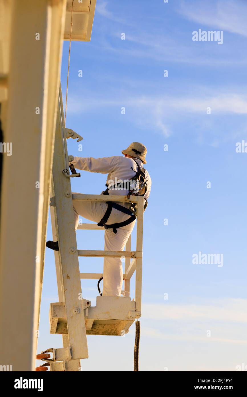 Ein Wartungsarbeiter in Sicherheitsausrüstung, der auf dem norwegischen Sun Kreuzfahrtschiff arbeitet, während er im Hafen von Santa Cruz de Tenerife, Kanarische Inseln, Spanien, festgemacht hat Stockfoto