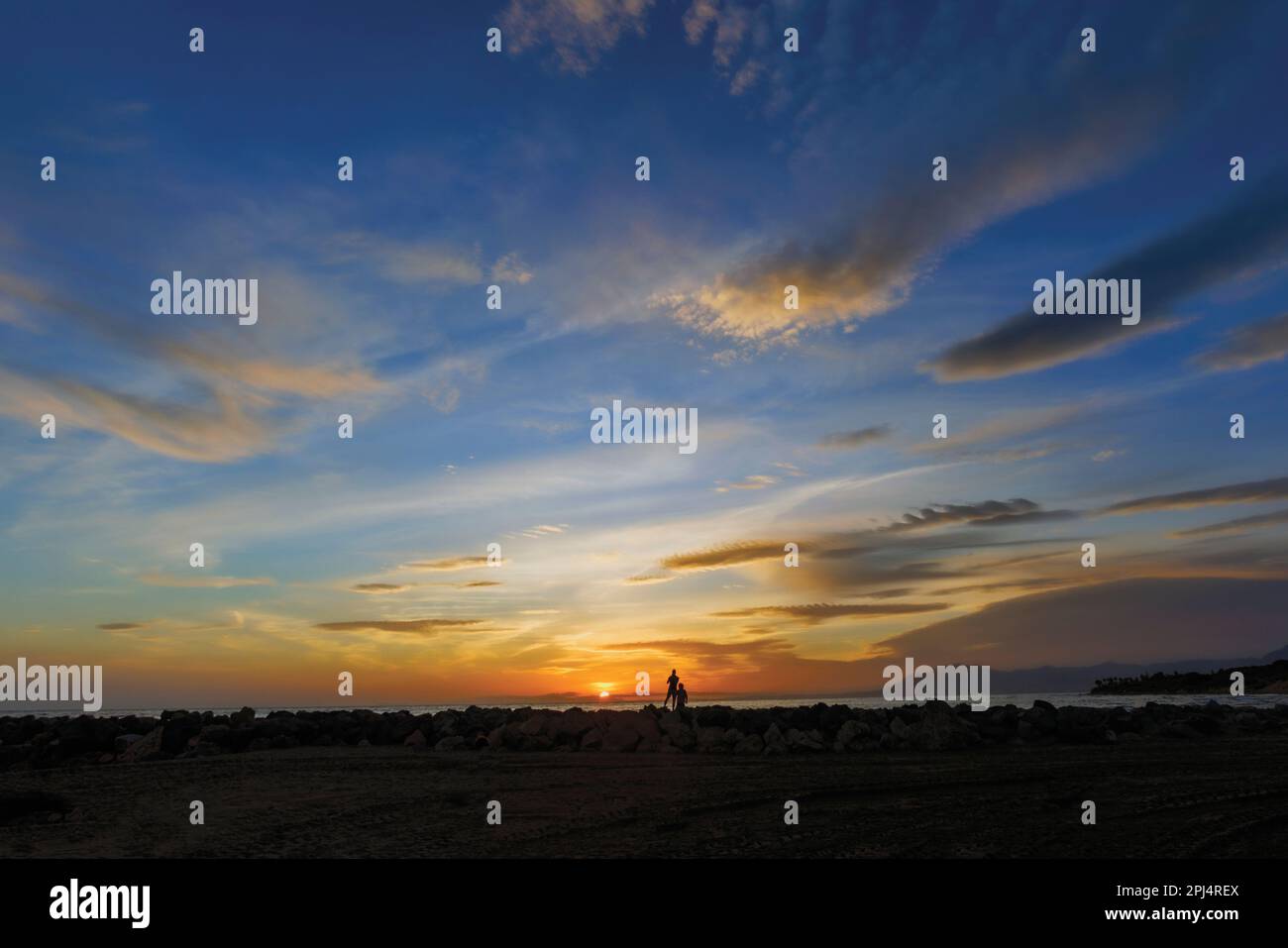 Zwei Menschen beobachten den Sonnenuntergang in der Nähe von Marbella, Provinz Malaga, Costa del Sol, Andalusien, Spanien. Stockfoto