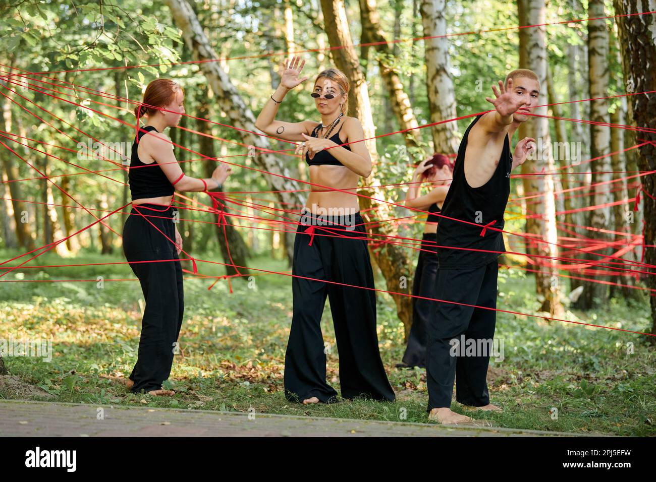 Svetlogorsk, Russland - 13.08.2022 - die Band der Darsteller wird in den roten Seilen im Park mit einer Outdoor-Kunstvorstellung im Wald über die menschliche Entscheidungsfreiheit verwirrt. Stockfoto
