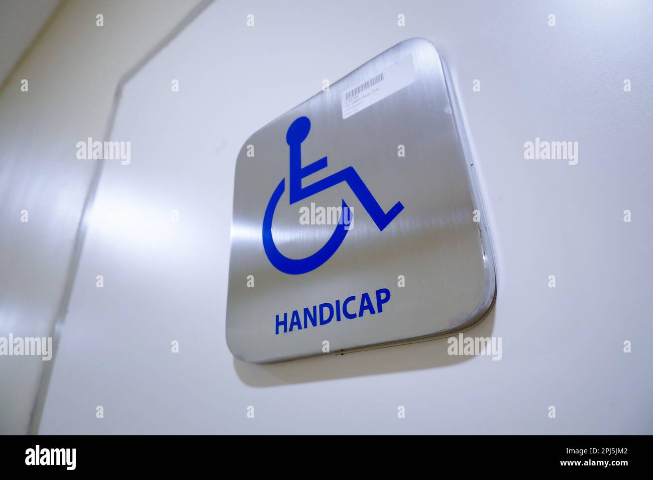Low-Angle-Aufnahme aus Edelstahl, Behindertentoilettenschild mit blauem Symbol. Fördert Zugänglichkeit und Inklusivität in öffentlichen Bereichen. Universell anerkannt Stockfoto