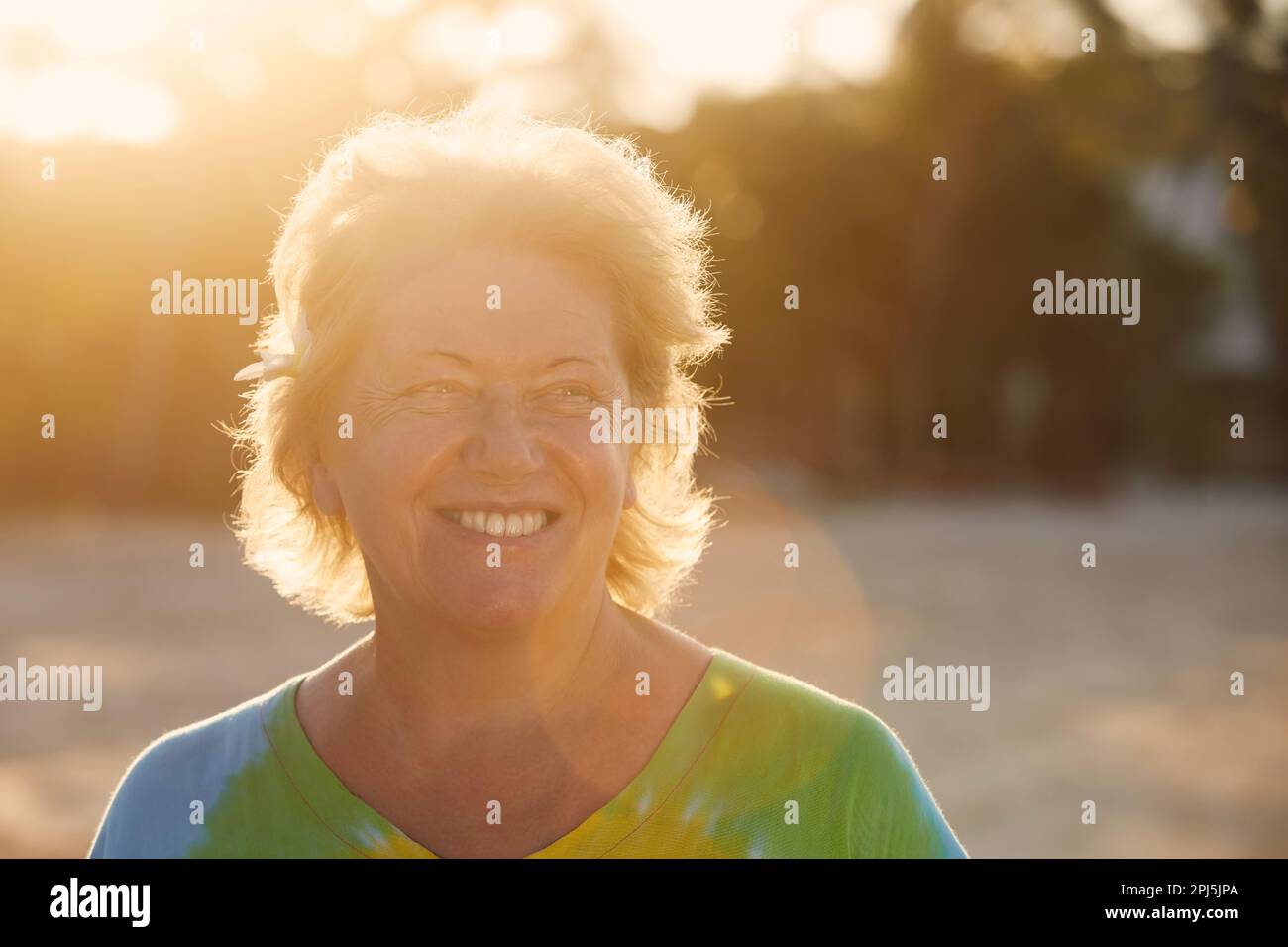 Porträt einer glücklichen Frau am Strand in einem tropischen Ziel bei Sonnenuntergang. Erfahrener Tourist in tropischen Gebieten. Stockfoto
