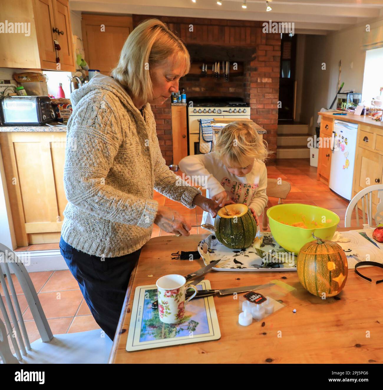 Eine Großmutter und ihre Enkelin machen Kürbislaternen für Halloween, England, Großbritannien Stockfoto