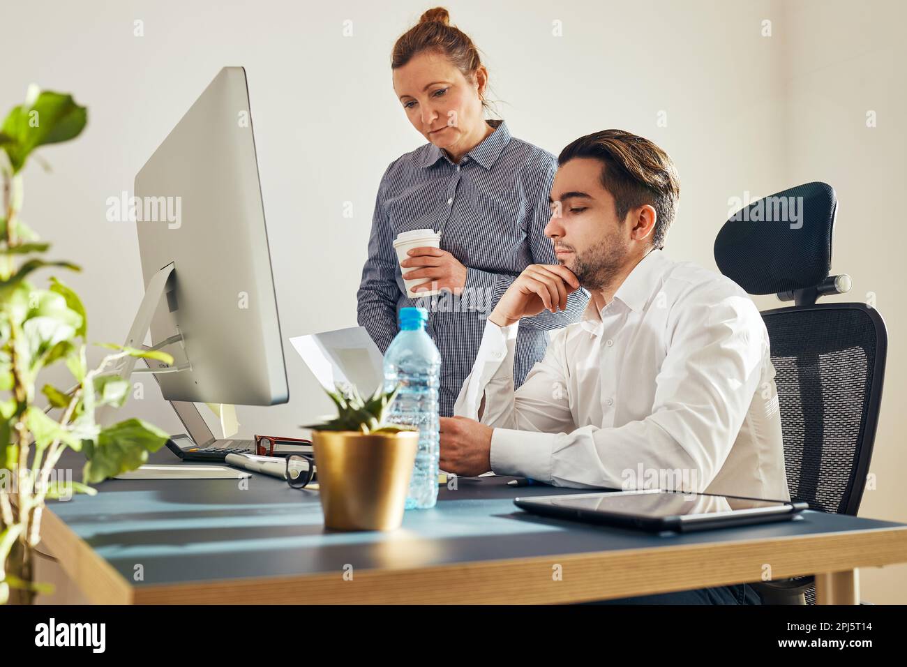 Zwei Geschäftsleute diskutieren Finanzdaten am Computer. Geschäftsfrau, die mit einem männlichen Kollegen im Büro zusammenarbeitet. Menschen Unternehmer arbeiten mit char Stockfoto