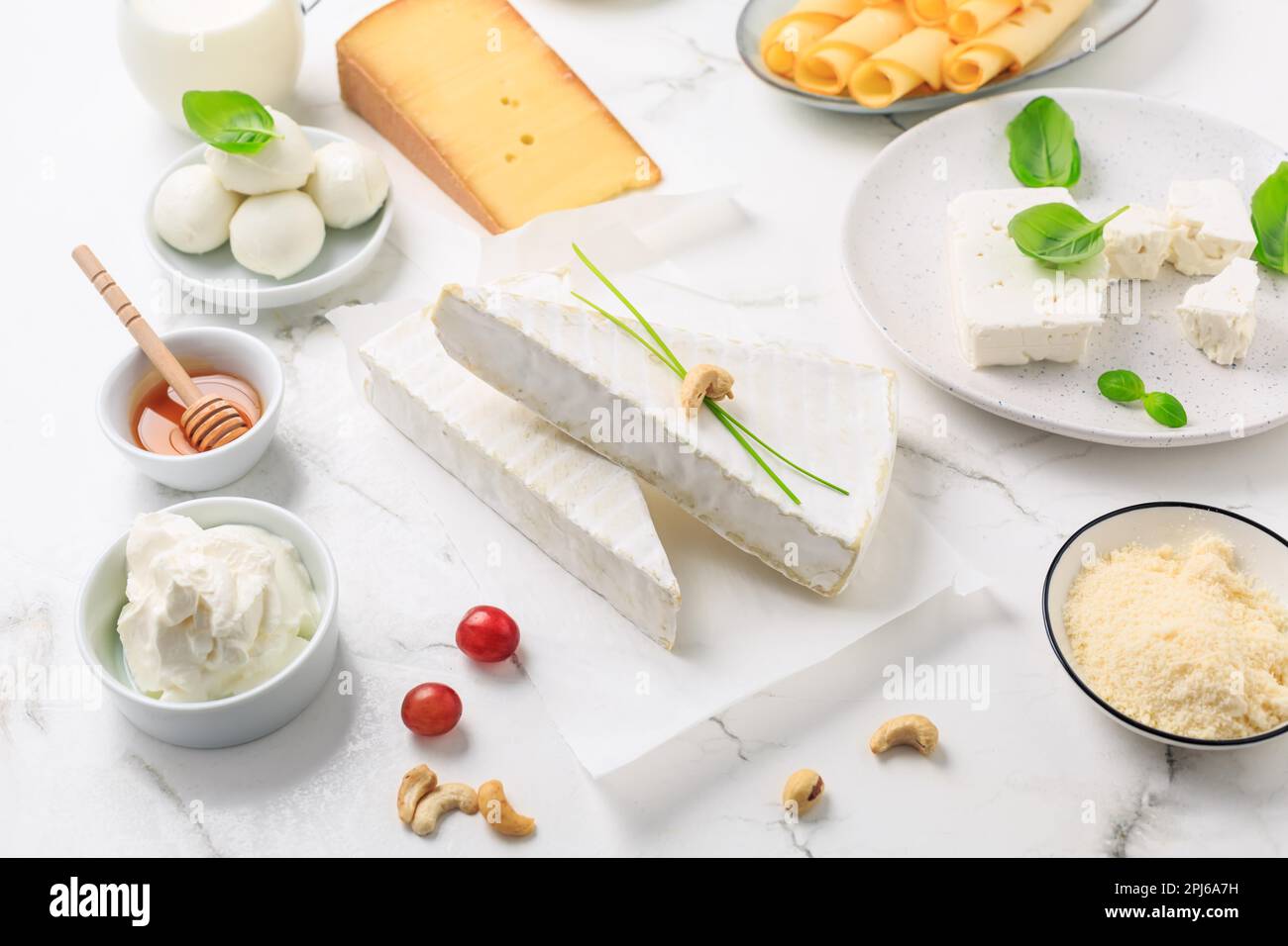 Frische Milchprodukte auf weißem Marmorhintergrund. Auswahl an Käse, Honig, Milch, Joghurt Stockfoto