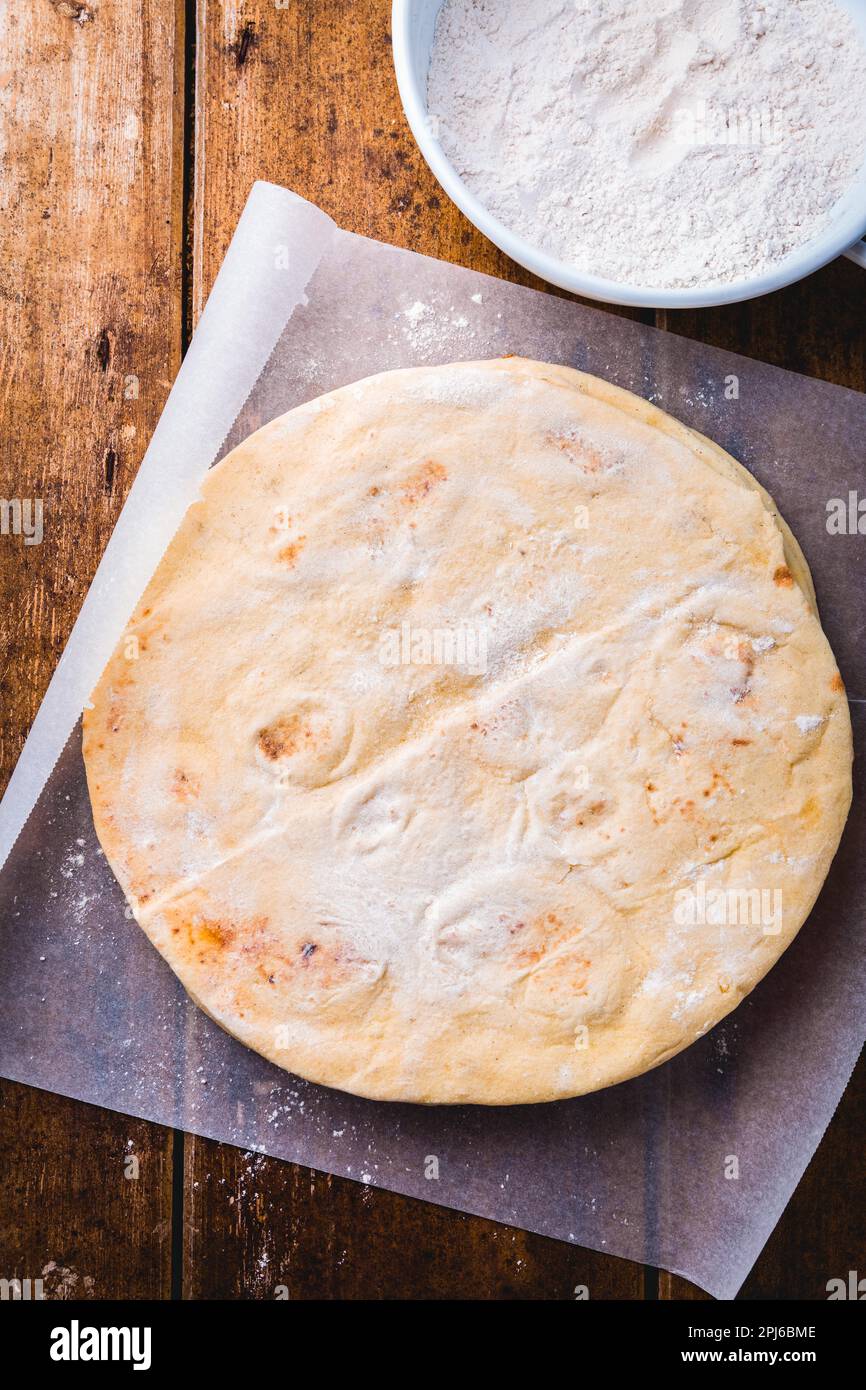 Fladenbrot, Pita oder Pizzabruste auf dem hölzernen Küchentisch Stockfoto