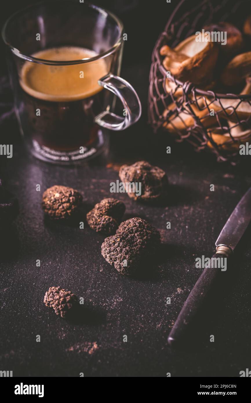 schwarzer-truffel-auf-dunklem-kuchentisch-mit-schwarzem-kaffee-und-pilzen-die-delikatesse-kochen-2pj6c8n.jpg