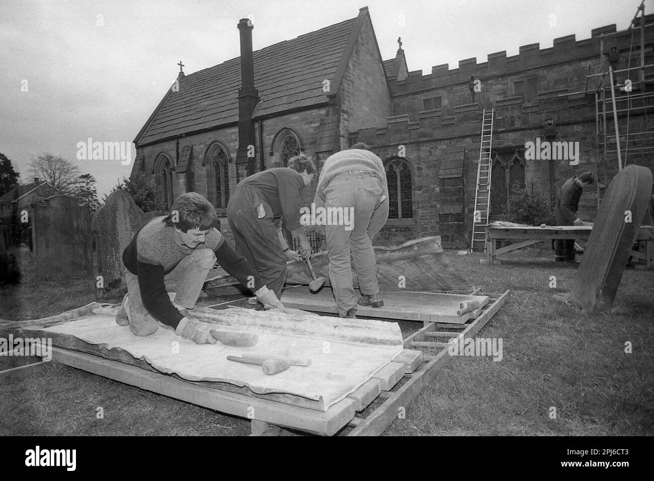 1986, historisch, draußen auf dem Gelände einer Kirche, Dachdecker, die mit Blei arbeiten, um das Dach einer Kirche zu reparieren, England, Großbritannien, und die Seiten des Materials heraushämmern. Aufgrund seiner hohen Verformbarkeit und seiner sehr langen Lebensdauer wird Blei seit Jahrhunderten in Kirchen und anderen historischen Gebäuden verwendet. Stockfoto