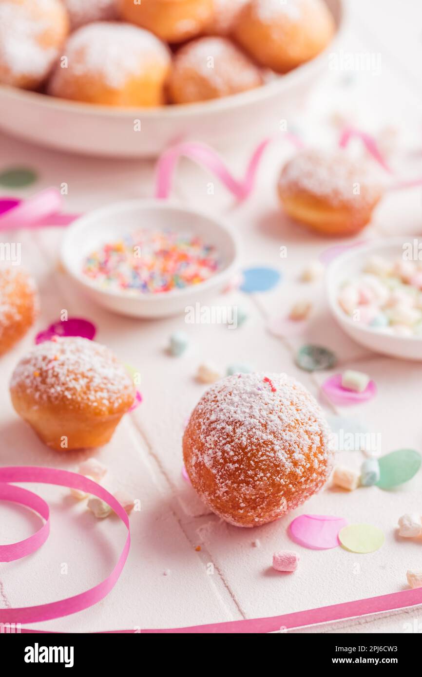 Krapfen, Berliner und Donuts mit Luftschlangen und Konfetti. Farbenfrohes Bild von Karneval, Geburtstag und Fasching Stockfoto