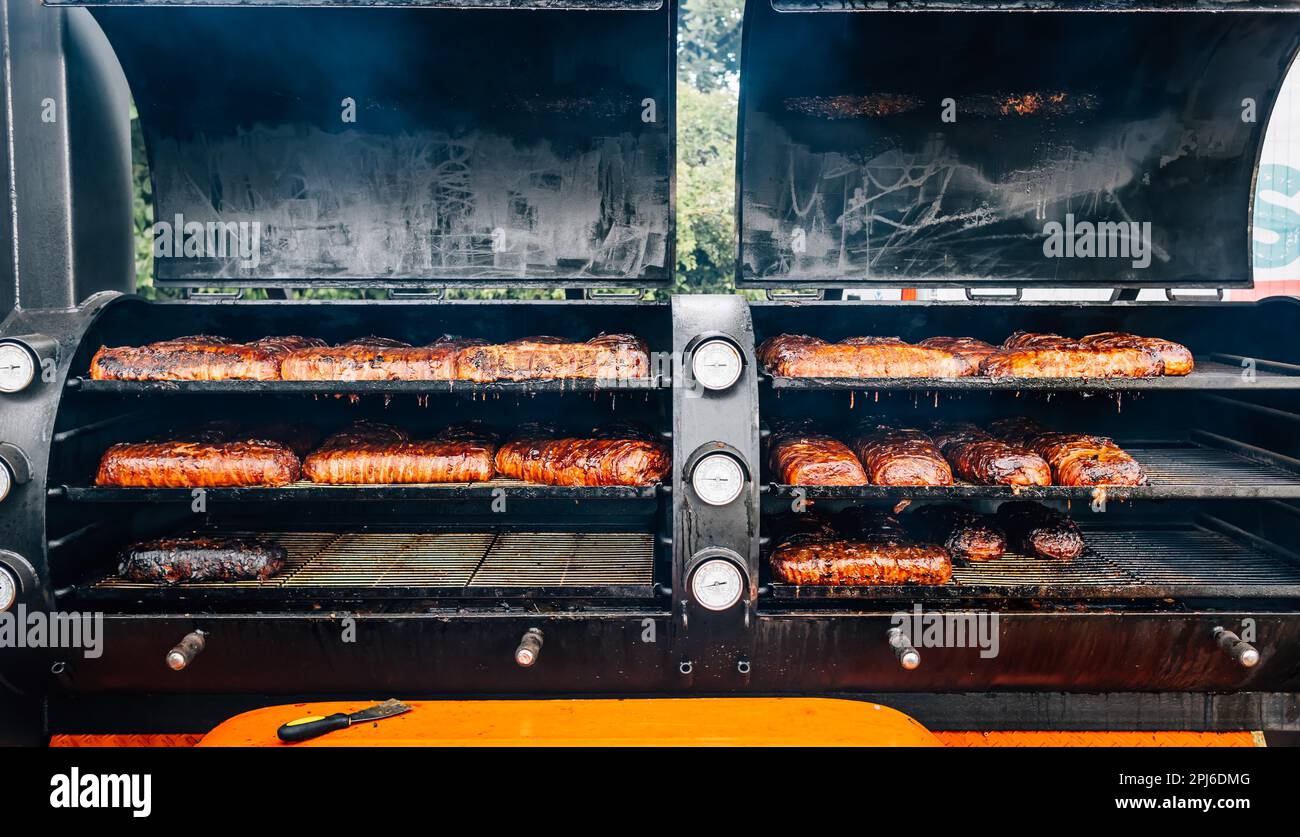 Großer Barbecue-Rauchergrill mit gegrilltem Fleisch und Speck. Straßenküche Stockfoto