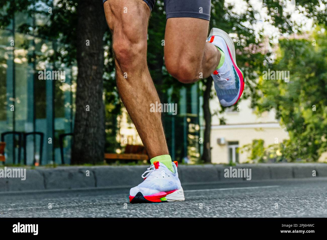 Nahaufnahmen der Beine männlicher Läufer läuft City Marathon-Rennen, Sportler joggen auf Asphaltstraße, Sommersportspiele Stockfoto