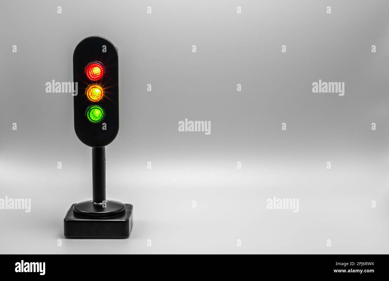 Miniatur-Ampel mit rotem, orangefarbenem und grünem Licht. Studioaufnahme. Silbergrauer leerer Hintergrund. Stockfoto
