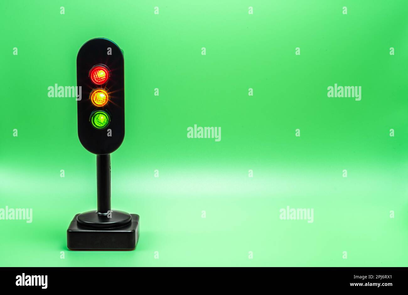 Miniatur-Ampel mit rotem, orangefarbenem und grünem Licht. Studioaufnahme. Smaragdgrün, leerer Hintergrund. Stockfoto
