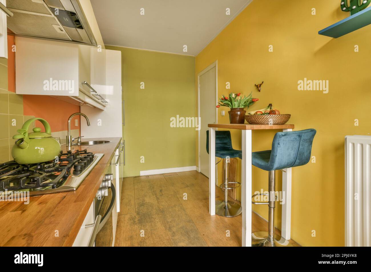 Küche und Essbereich in einem Haus mit gelben Wänden, Holzfußboden und weißen Geräten an der Wand Stockfoto