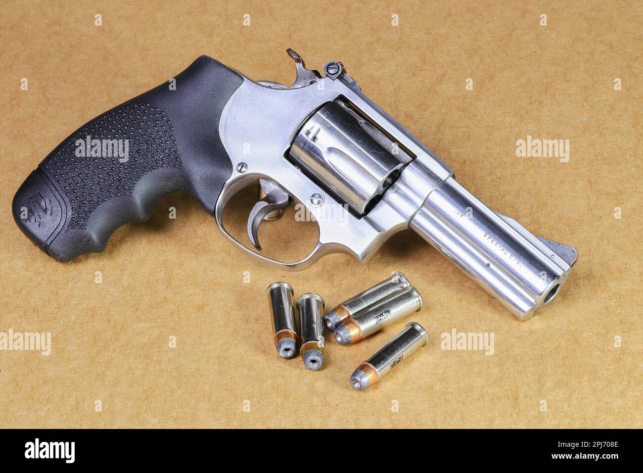 Die kompakte Revolverpistole, J-Rahmen aus Edelstahl, M60-Pistole, Vorderansicht rechts, mit Schließzylinder, isoliert auf braunem Hintergrund für den Einsatz vorbereitet. Stockfoto
