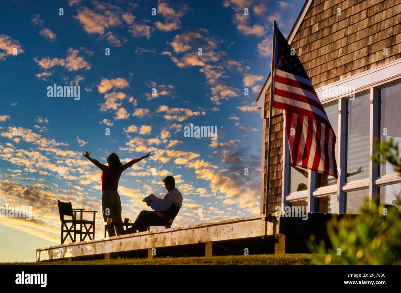 Ein Paar, das sich bei Sonnenuntergang auf dem Deck des Verifizierungshauses entspannt Stockfoto