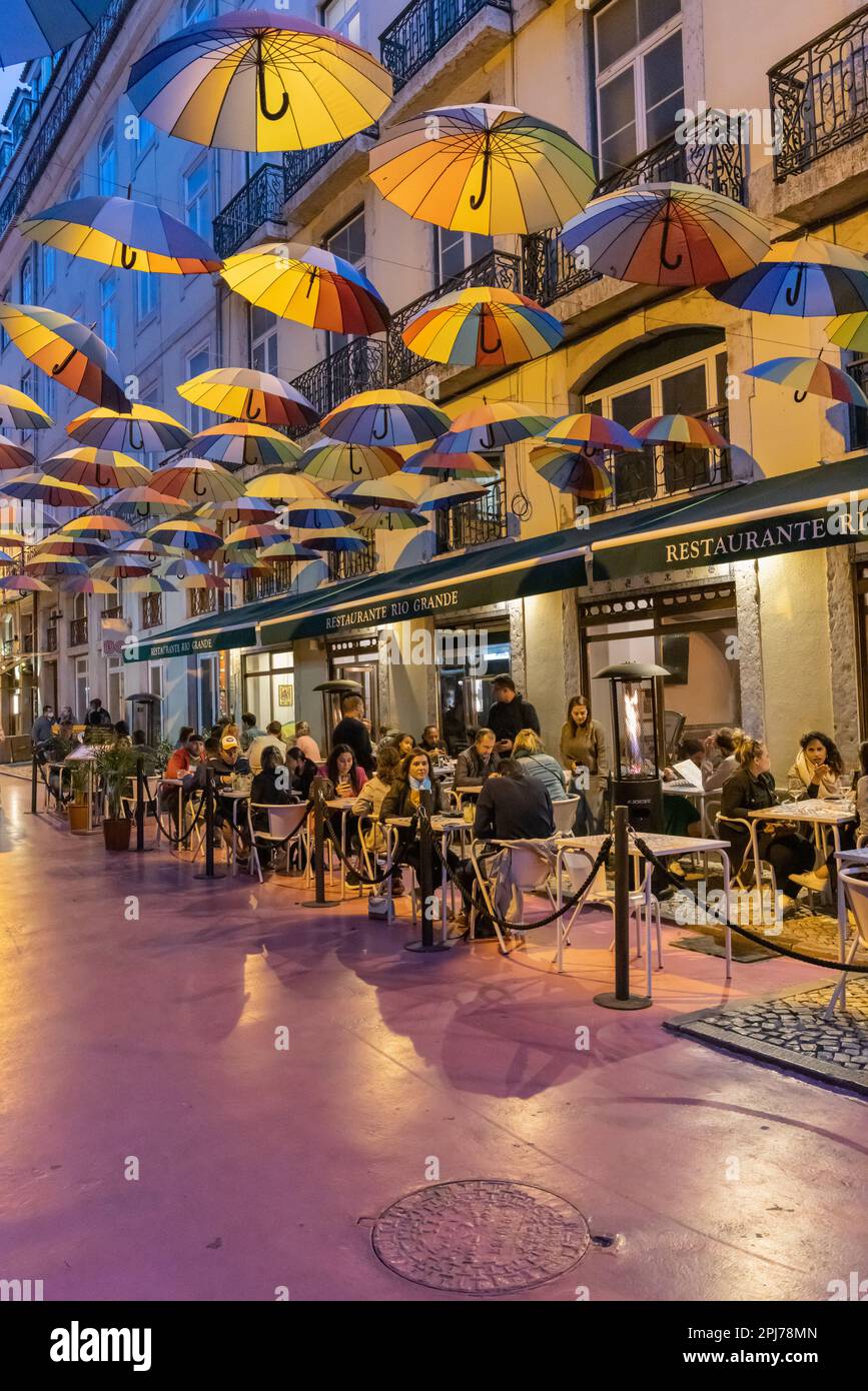 Europa, Portugal, Lissabon. 18. April 2022. Farbenfrohe Sonnenschirme über Cafés an einer Fußgängerzone in Lissabon. Stockfoto