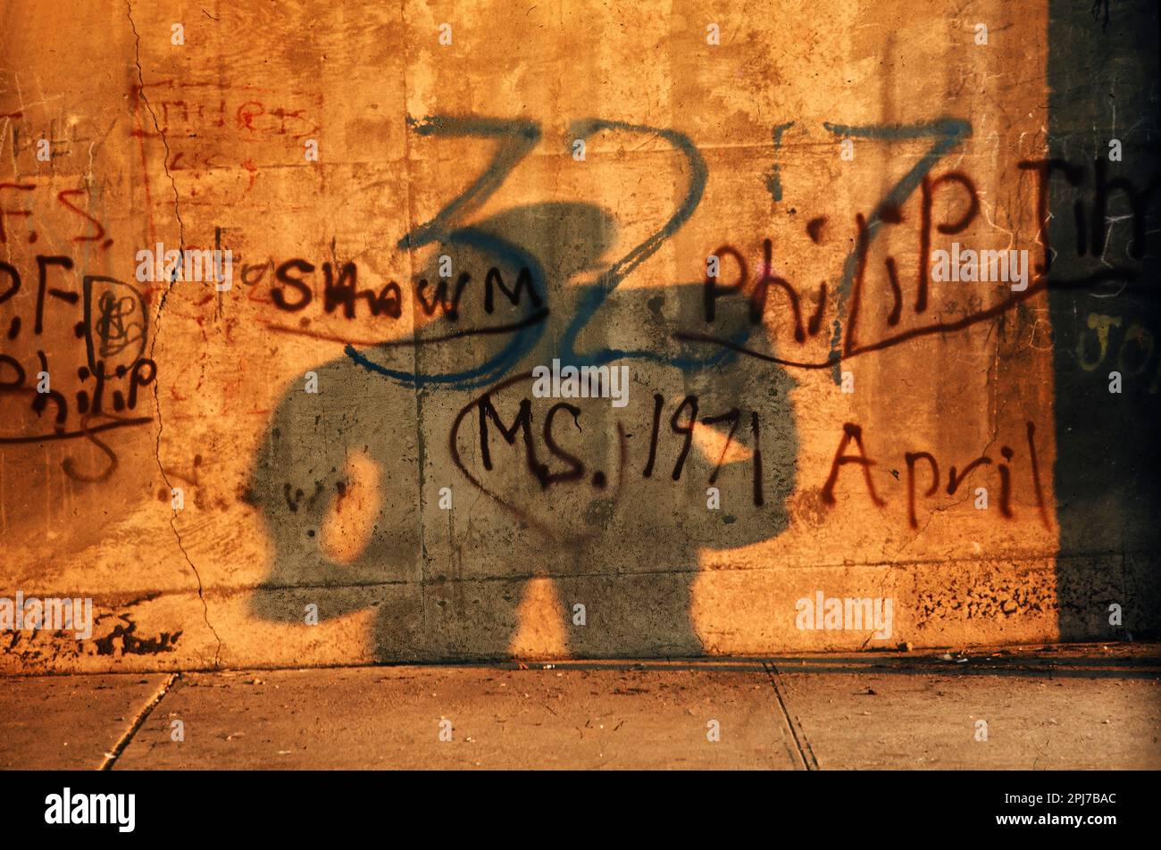 Störende Silhouette einer Person gegen eine graffiti-bedeckte städtische Betonwand Stockfoto