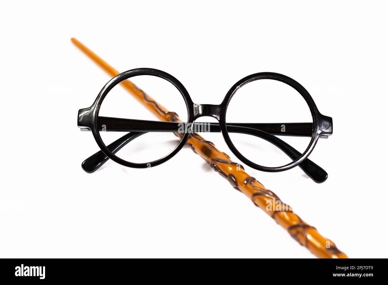 Runde schwarze Brille und brauner Zauberstab isoliert auf weißem Hintergrund. Stockfoto
