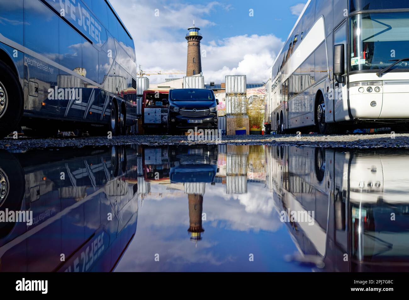 Köln, Deutschland April 7 2022: Tourbusse und Minibusse eines Festivals auf dem helios-Gelände in ehrenfeld spiegeln sich in einer Pfütze wider Stockfoto