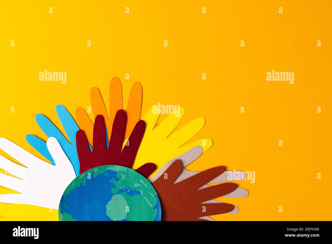 Aus mehrfarbigen Händen und Globus geschnittenes Papier mit Kopierbereich auf gelbem Hintergrund Stockfoto