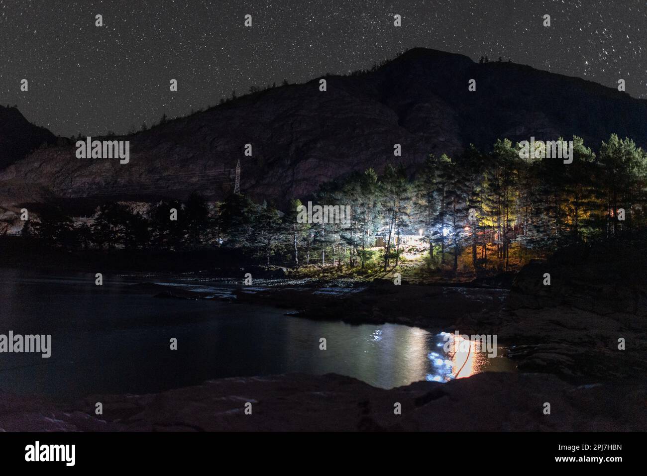 Das steinerne Ufer der Bucht des Katun Flusses in den Schatten bei Nacht nahe der Berghaube beleuchtet durch das Licht der anderen Häuser Stockfoto