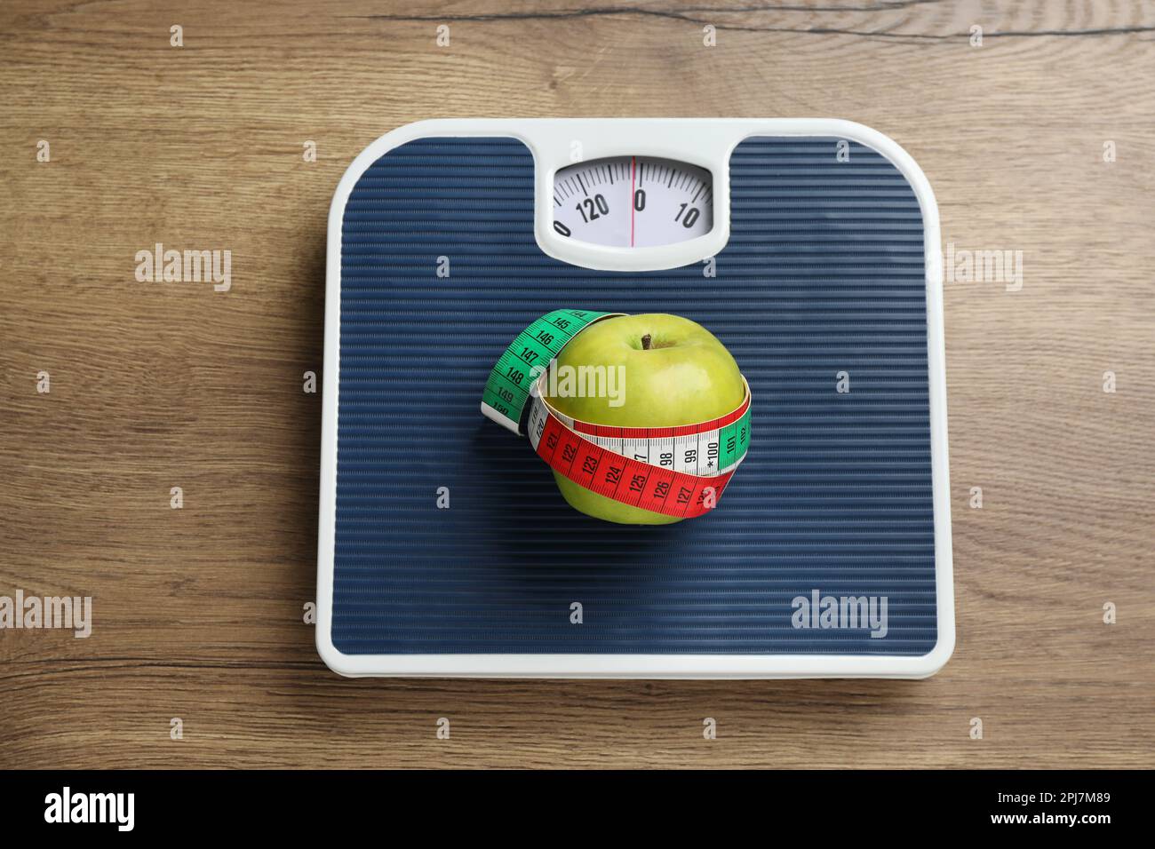 Waagen mit Apfel und Maßband auf Holztisch, Draufsicht. Gewichtsverlust Stockfoto