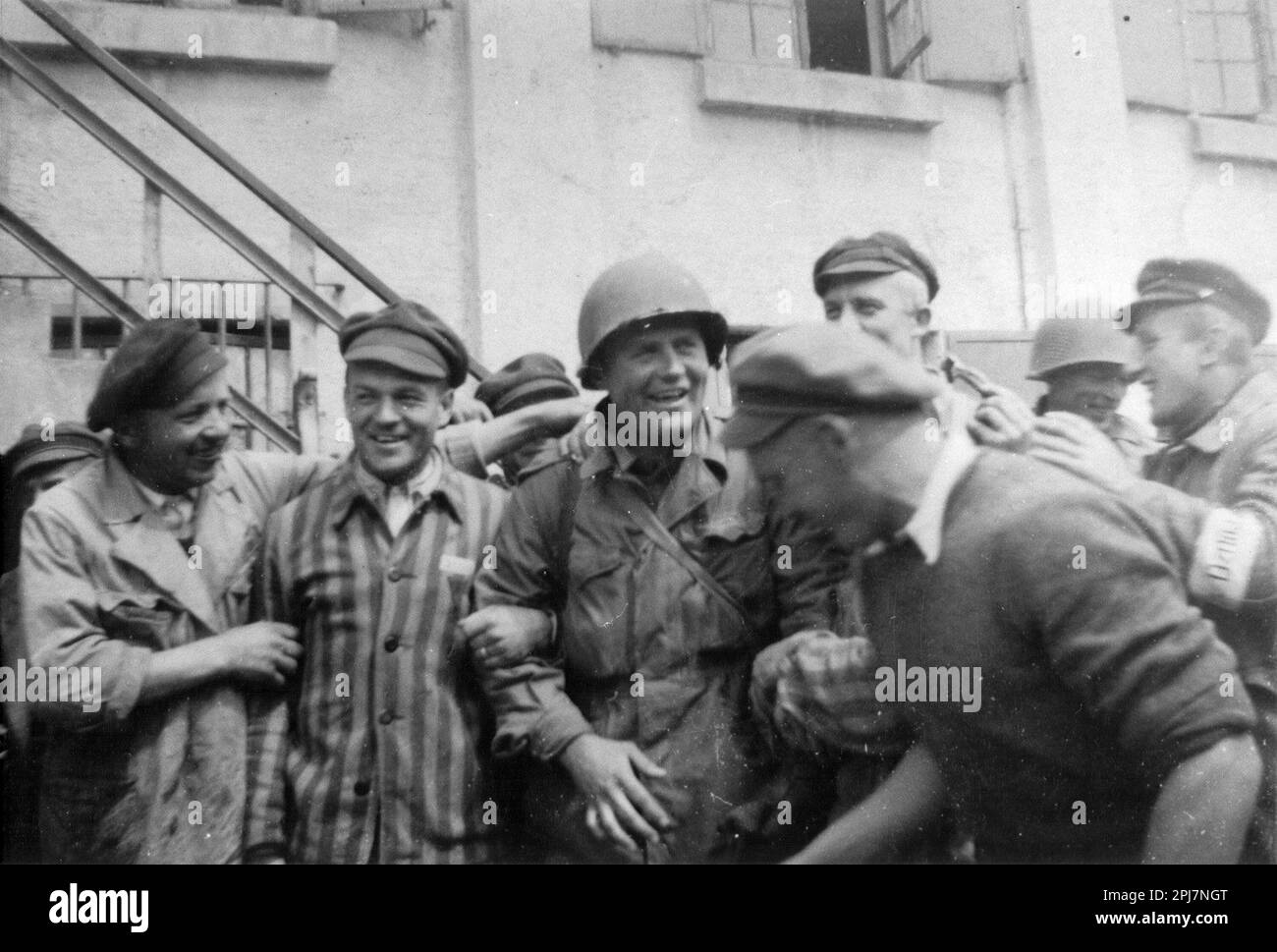 Ein amerikanischer Soldat ist umgeben von Überlebenden im neu befreiten Konzentrationslager Dachau, 29. April 1945 in Dachau, Deutschland. Amerikanische Soldaten der 7. US-Armee, darunter Mitglieder der 42. Infanterie, 45. Infanterie und 20. Panzerdivisionen, nahmen an der Befreiung des Lagers Teil. Stockfoto