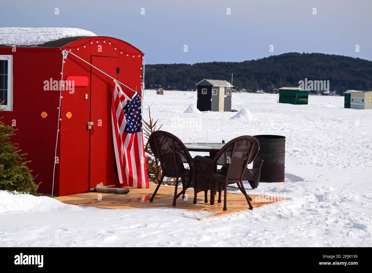 Terrassenmöbel sind in einer unwahrscheinlichen Lage aufgestellt: Außerhalb einer Hütte zum Eisfischen am Lake Winnipesaukee, New Hampshire im Winter Stockfoto