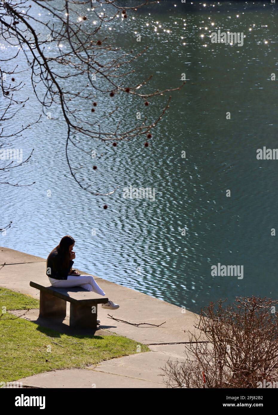 Junge Frau sitzt bei Wade Lagoon am University Circle in Cleveland, Ohio Stockfoto