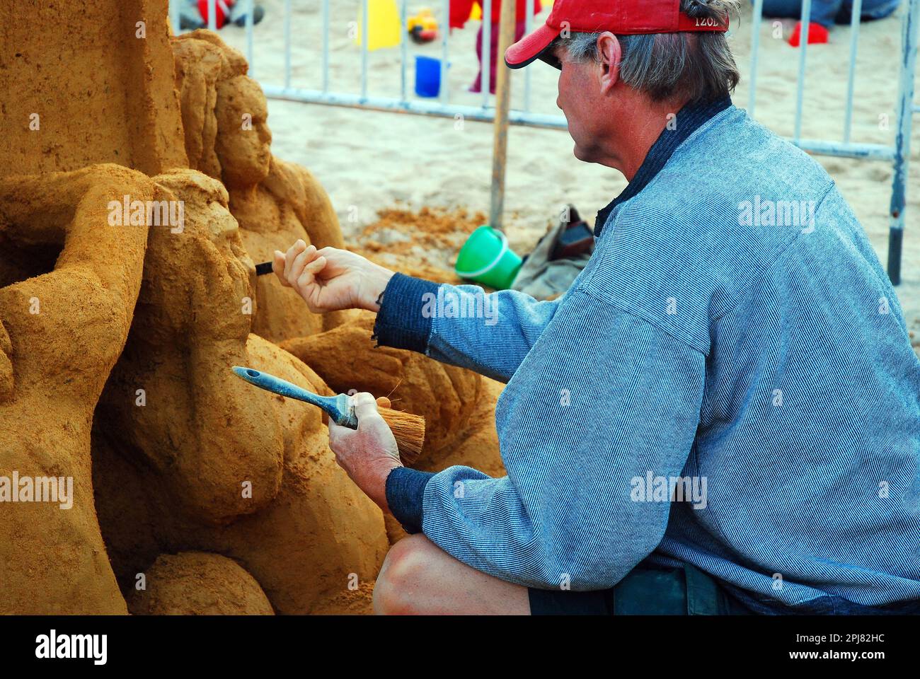 Ein Bildhauer schneidet die Details einer Sandburg heraus Stockfoto