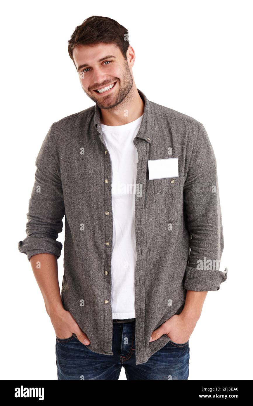 Dieses Namensschild kannst du ausfüllen. Studio-Porträt eines lächelnden jungen Mannes mit einem leeren Namensschild, der mit den Händen in den Taschen steht. Stockfoto
