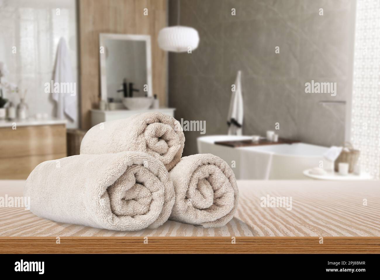 Gerollte beige Handtücher auf Holztisch im Badezimmer. Platz für Text ... Gerollte beige Handtücher auf Holztisch im Badezimmer. Platz für Text ...