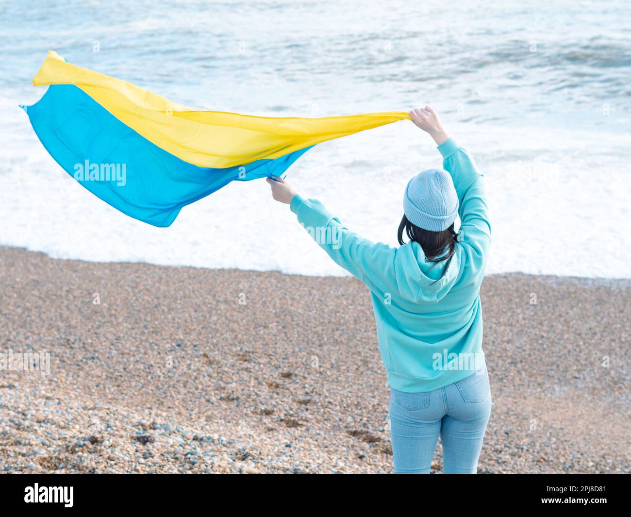Braune Frau in blauem Hoodie und blauem Hut mit ukrainischer Nationalflagge, patriotisches Konzept Stockfoto