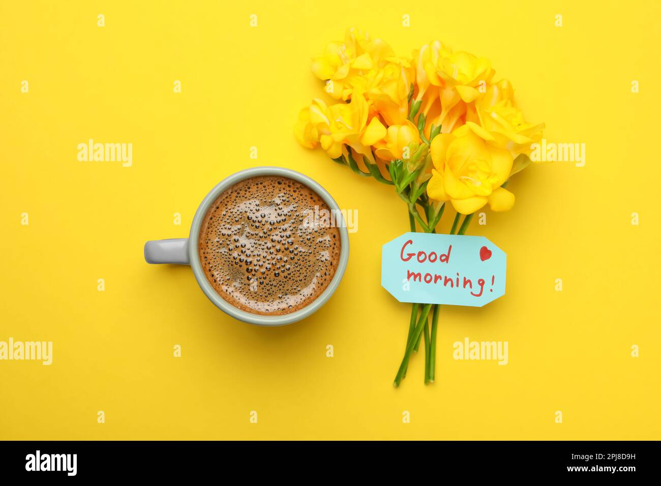 Tasse aromatischer Kaffee, wunderschöne Freesias und Good Morning Note auf gelbem Hintergrund, flach liegend Stockfoto