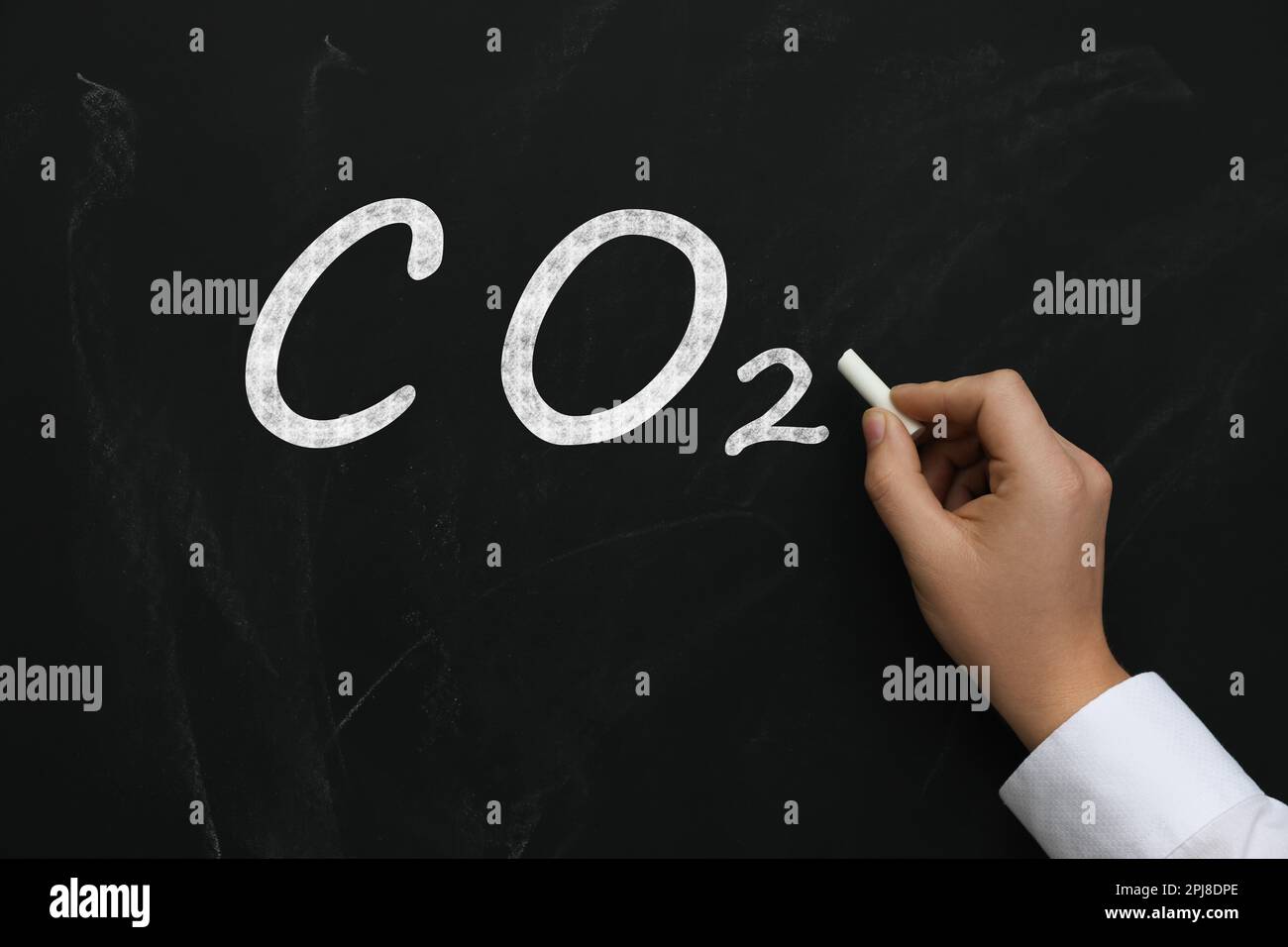 Reduzierung der Kohlenstoffemissionen. Frau schreibt chemische Formel CO2 auf Tafel, Nahaufnahme Stockfoto