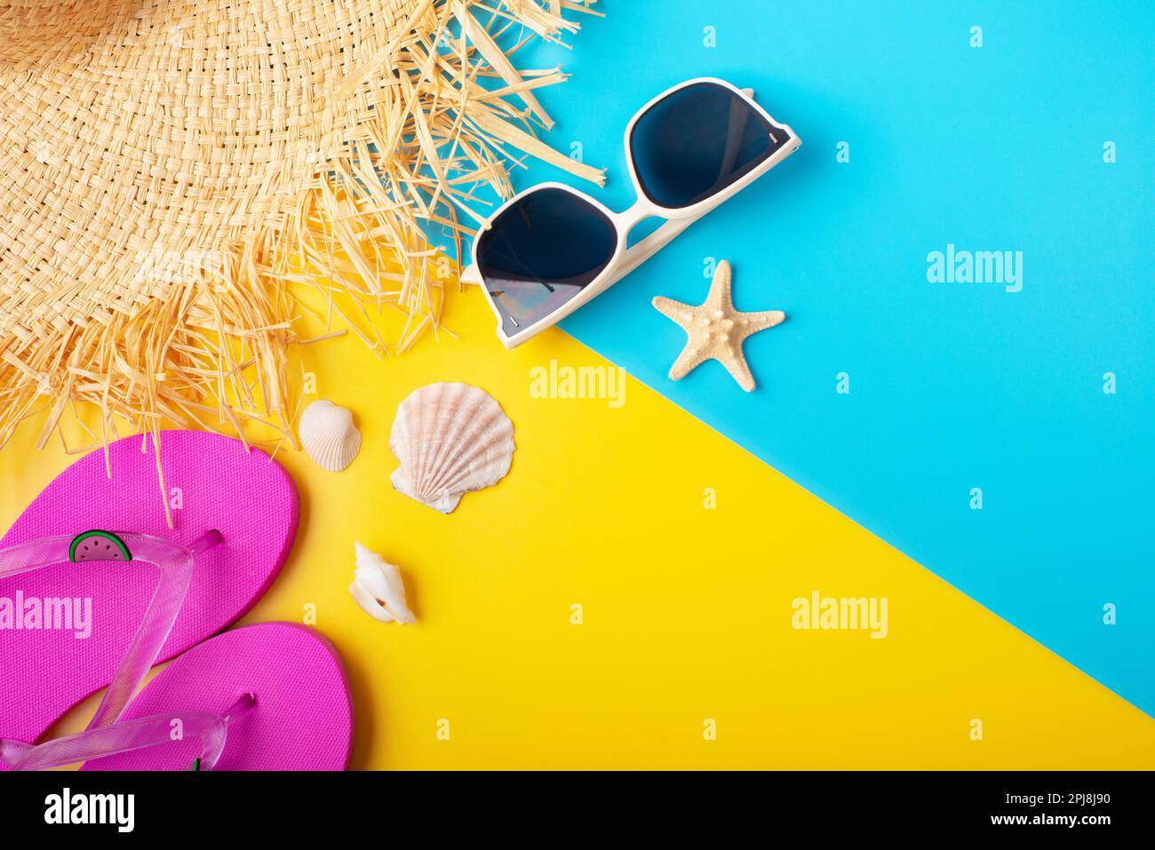Strohhut Sonnenbrillen Flip-Flops und Muscheln auf gelbem und blauem Hintergrund Reiseplanungsmodell Stockfoto