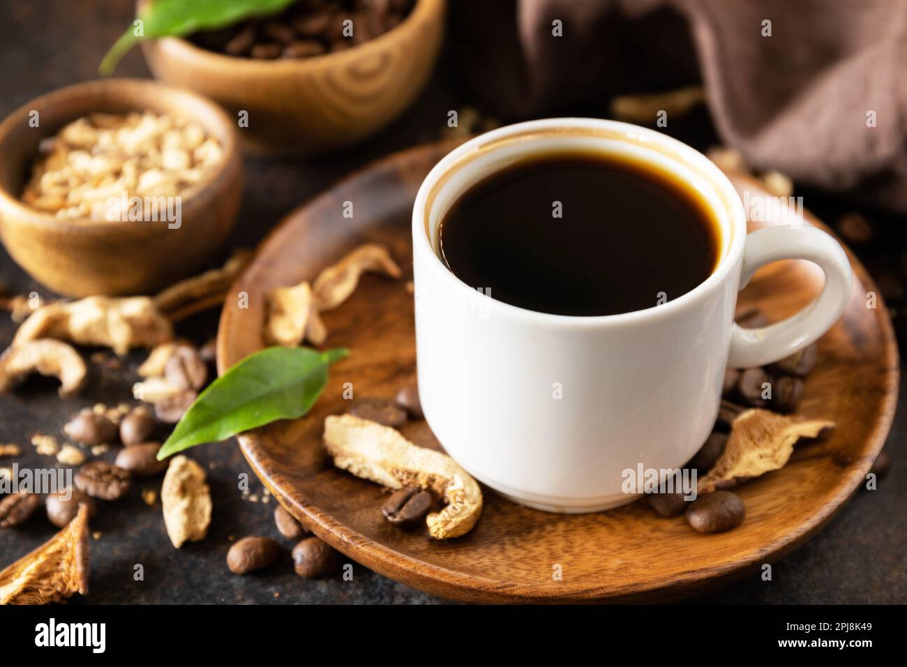 Pilzkaffee in einer Tasse und Kaffeebohnen, trendiges Getränk auf Steinhintergrund. Gesundes organisches energiegeladenes Adaptogen. Stockfoto