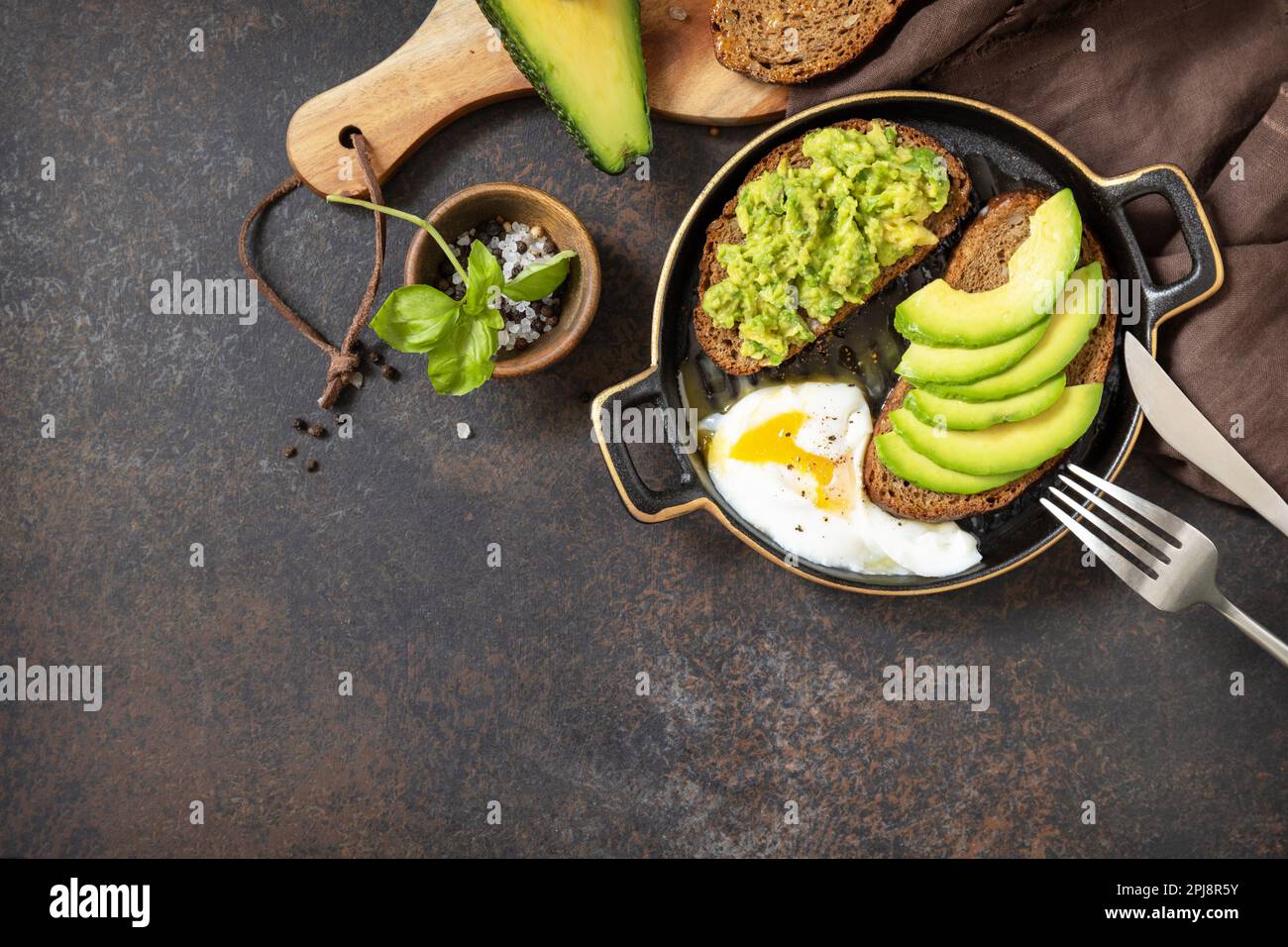 Gesundes Frühstückskonzept, Sandwich mit Avocado und Ei, Vollkornbrot, Avocado in Scheiben und pochiertes Ei auf Steinhintergrund. Blick von oben. Stockfoto