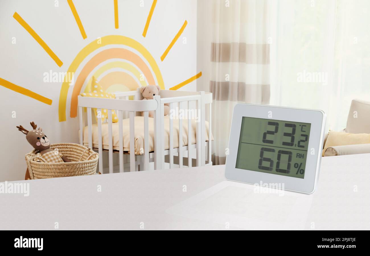 Digitales Hygrometer mit Thermometer auf weißem Tisch im Kinderzimmer