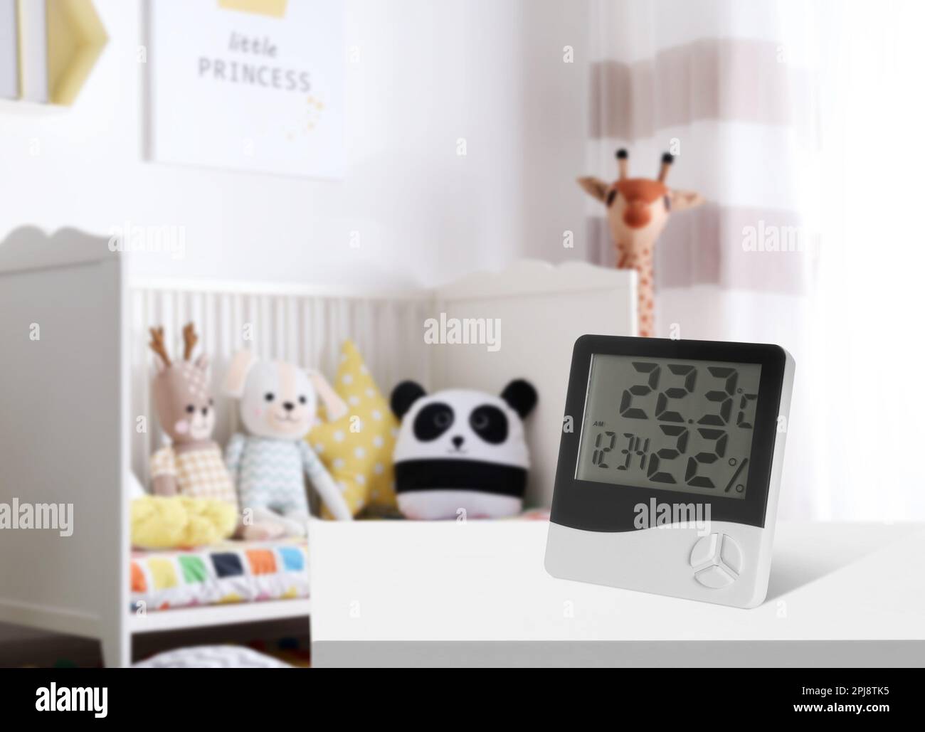 Digitales Hygrometer mit Thermometer auf weißem Tisch im Kinderzimmer. Niedrige Luftfeuchtigkeit für Kinder Stockfoto