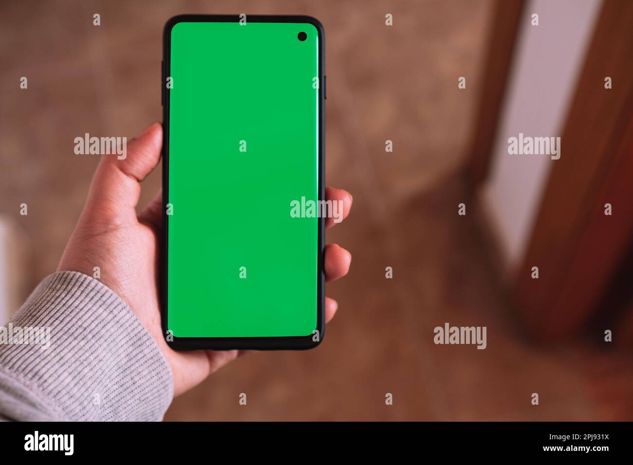Weibliche Hand mit grünem Smartphone-Bildschirm. Chroma Key Telefonbildschirm in vertikaler Position. Fotomodell mit Kopierbereich. Internet der Dinge. Stockfoto