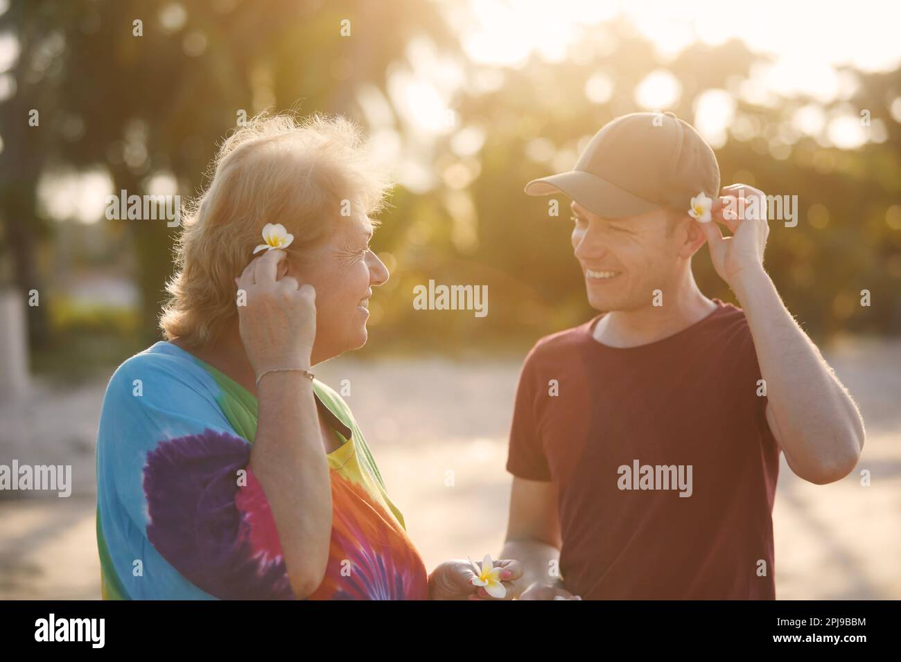 Glückliche Seniorin mit ihrem erwachsenen Sohn zusammen am Strand bei wunderschönem Sonnenuntergang. Touristen in tropischen Gebieten. Stockfoto