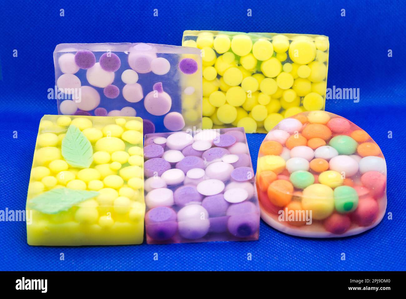 Drei transparente Seifenstücke mit leuchtend bunten Kugeln auf blauem Hintergrund. Stockfoto